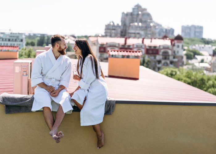 flirting couple with sparkling wine on a roof, sits on the edge of the balcony